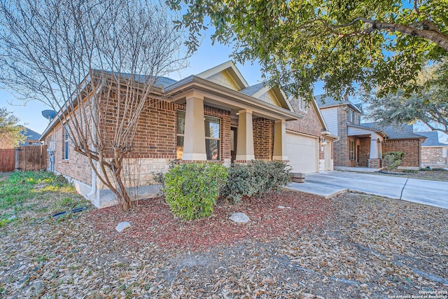 view of front of home with a garage, concrete driveway, covered porch, fence, and brick siding