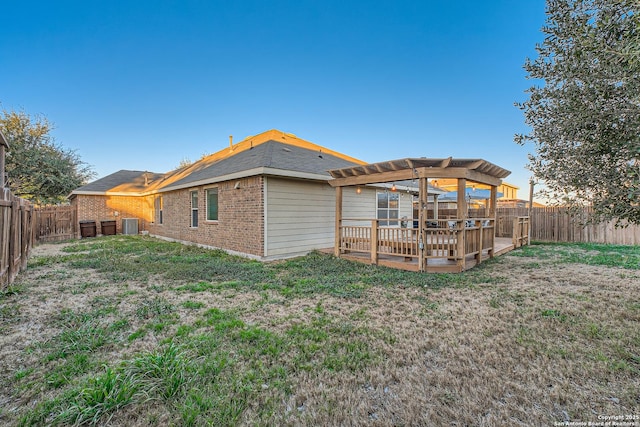 back of house with a fenced backyard, a pergola, a lawn, and brick siding