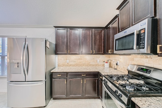 kitchen featuring dark brown cabinetry, light stone counters, stainless steel appliances, and backsplash