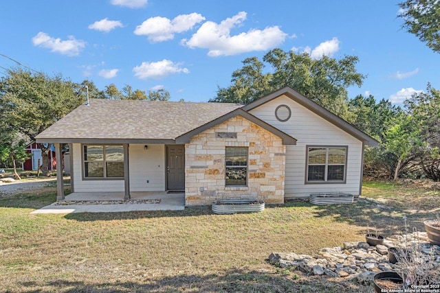 view of front of property with a shingled roof, stone siding, and a front lawn