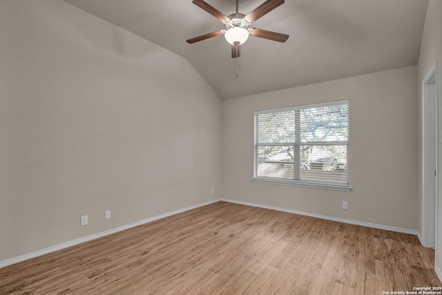 empty room with vaulted ceiling, a ceiling fan, light wood-style flooring, and baseboards