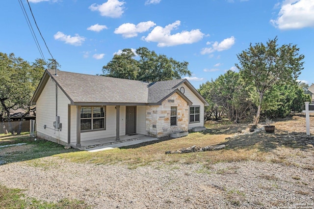 view of front facade featuring stone siding and roof with shingles