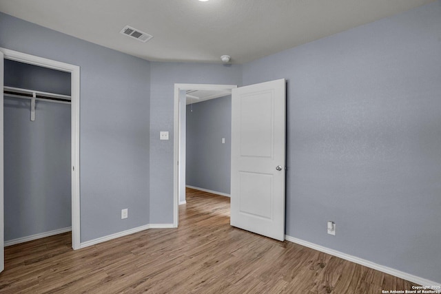 unfurnished bedroom with a closet, baseboards, visible vents, and light wood finished floors