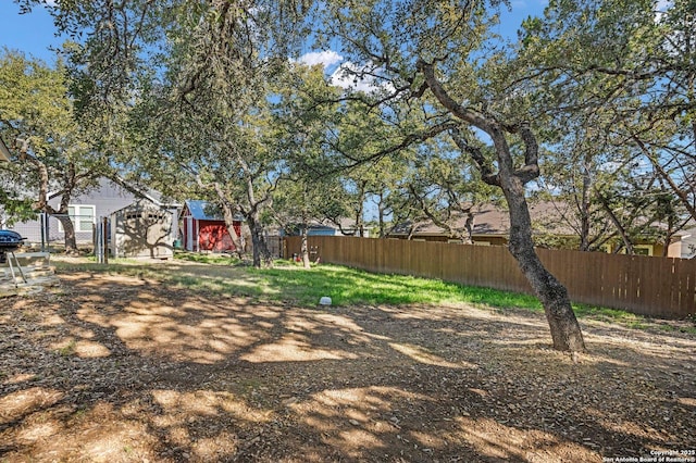 view of yard with a fenced backyard, a storage unit, and an outbuilding