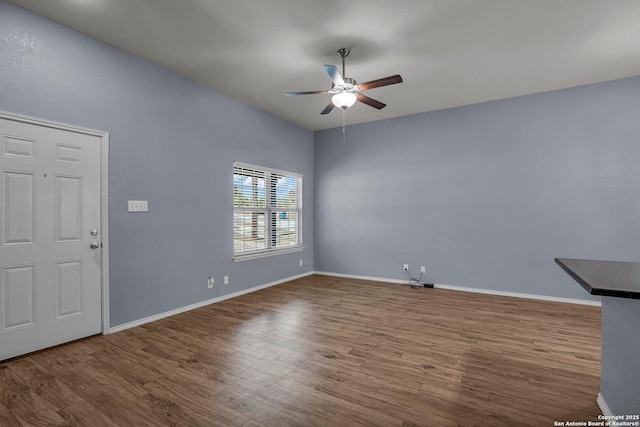 foyer with dark wood-style flooring, a ceiling fan, and baseboards