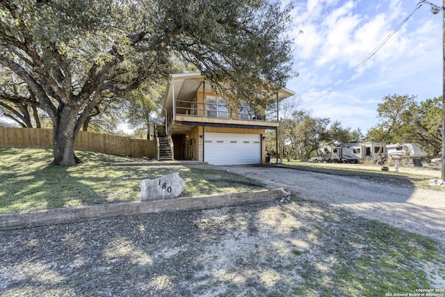 view of front of property with fence, stairway, a front yard, a garage, and driveway