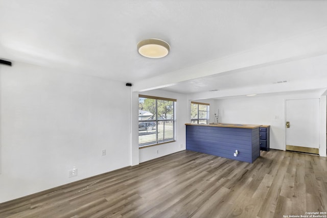 unfurnished living room featuring visible vents, beam ceiling, and wood finished floors