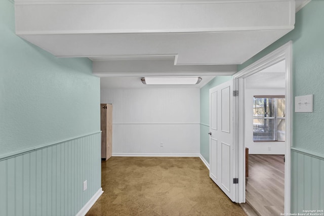 hallway featuring a wainscoted wall and carpet floors