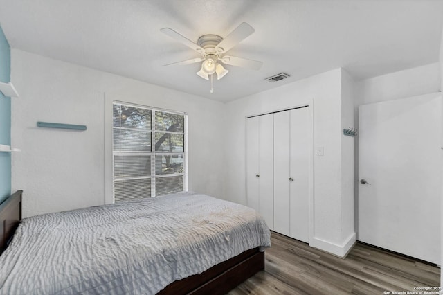 bedroom with a closet, visible vents, wood finished floors, and a ceiling fan