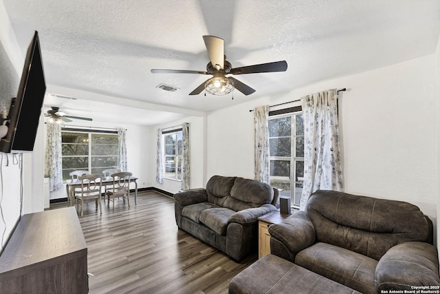 living area with wood finished floors, visible vents, a wealth of natural light, and a textured ceiling