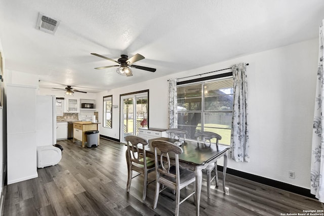 dining area with visible vents, dark wood-type flooring, a textured ceiling, baseboards, and ceiling fan