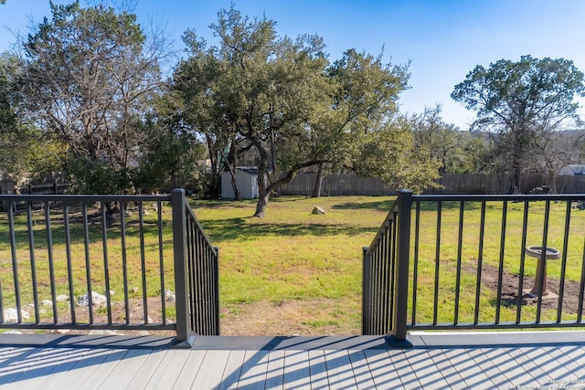 view of gate with a storage shed, a fenced backyard, a yard, and an outbuilding