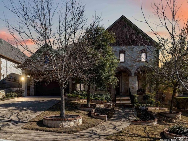 view of front facade featuring driveway, stone siding, and a garage