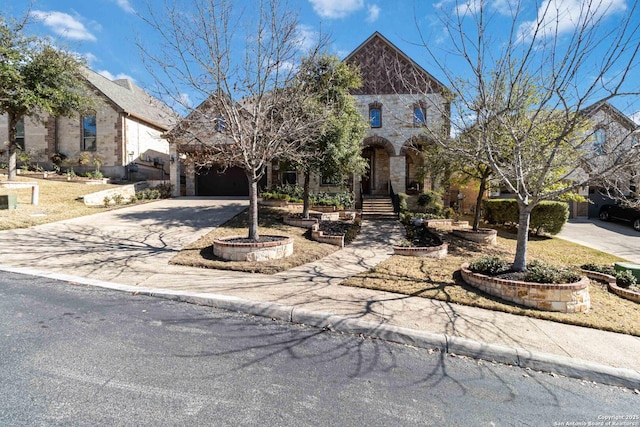 french country style house featuring a garage, driveway, and stone siding