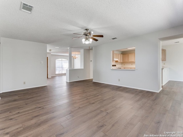 unfurnished living room with visible vents, wood finished floors, and ceiling fan with notable chandelier