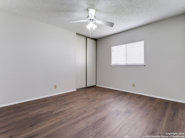 unfurnished room featuring ceiling fan, a textured ceiling, baseboards, and dark wood-type flooring