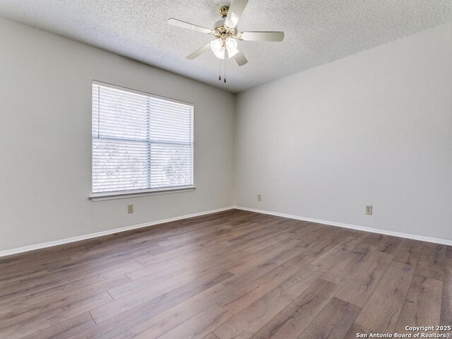 spare room featuring ceiling fan, baseboards, dark wood finished floors, and a textured ceiling