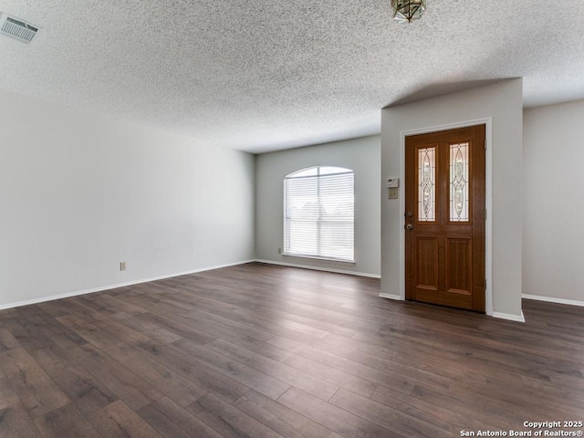 entryway featuring a textured ceiling, dark wood finished floors, visible vents, and baseboards