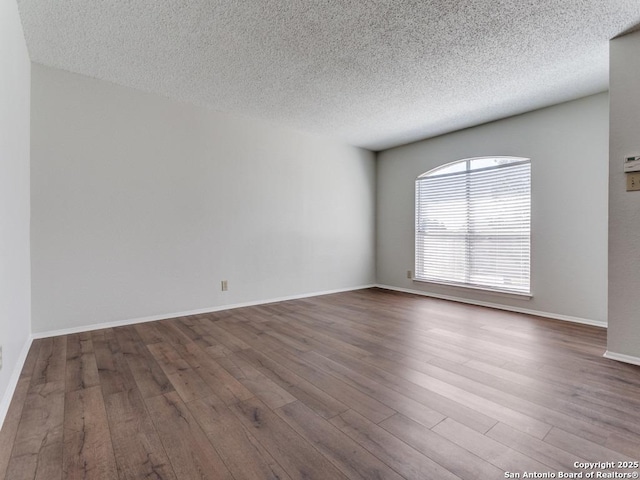 unfurnished room featuring a textured ceiling, wood finished floors, and baseboards