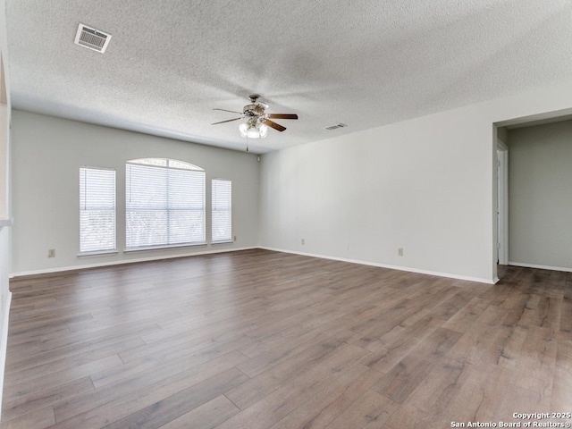 empty room featuring baseboards, visible vents, ceiling fan, and light wood finished floors