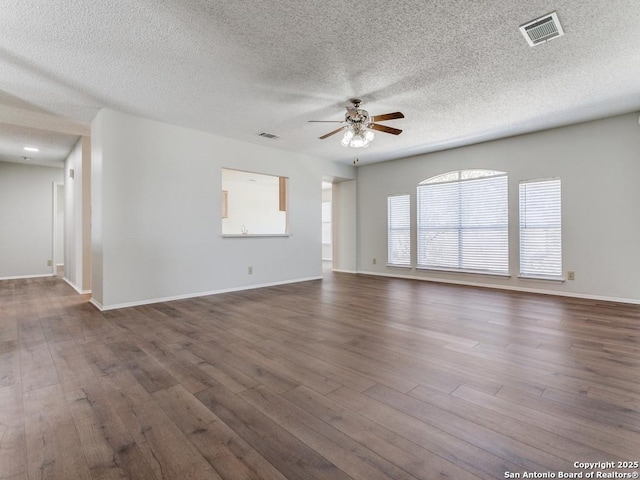 unfurnished living room with ceiling fan, dark wood-type flooring, visible vents, and baseboards