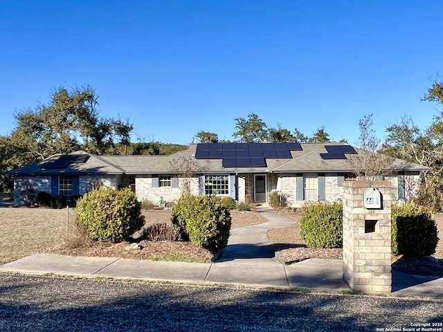 ranch-style house with roof mounted solar panels