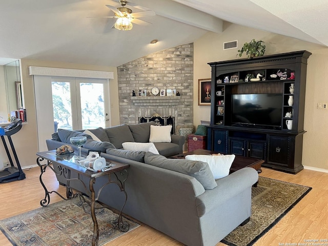 living area with lofted ceiling with beams, light wood finished floors, a fireplace, and visible vents