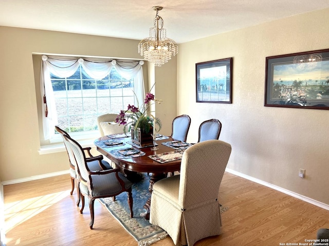 dining space featuring baseboards, wood finished floors, and an inviting chandelier