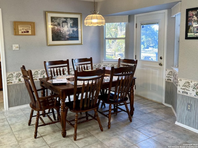 dining area featuring wallpapered walls and wainscoting