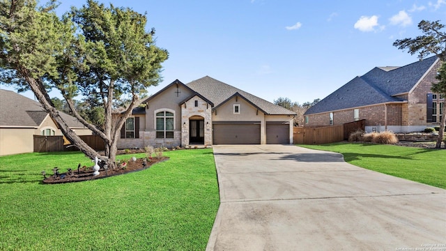 french country style house featuring driveway, stone siding, an attached garage, fence, and a front yard