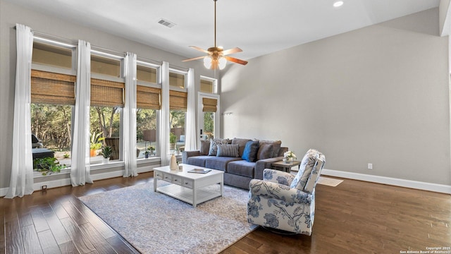 living room featuring dark wood-style flooring, visible vents, a high ceiling, ceiling fan, and baseboards