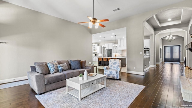 living room with arched walkways, dark wood-style floors, visible vents, and baseboards