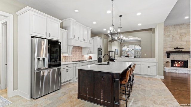 kitchen featuring a sink, a kitchen breakfast bar, white cabinets, light countertops, and appliances with stainless steel finishes