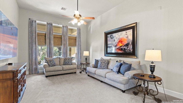 living room with baseboards, a ceiling fan, visible vents, and light colored carpet