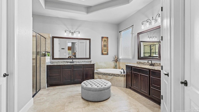 bathroom featuring two vanities, a sink, a bath, a tray ceiling, and a stall shower