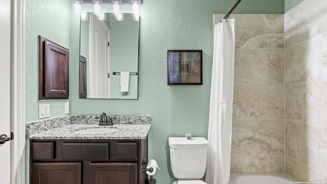 bathroom featuring a textured wall, shower / tub combo, vanity, and toilet