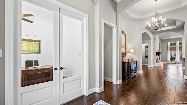 foyer featuring baseboards, arched walkways, dark wood-type flooring, french doors, and a notable chandelier