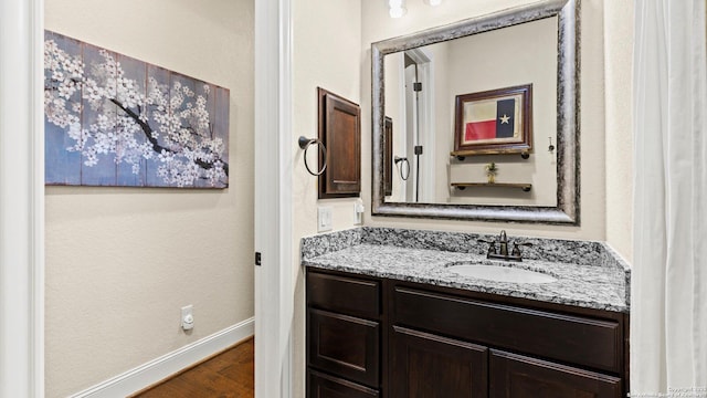 bathroom featuring baseboards, wood finished floors, and vanity