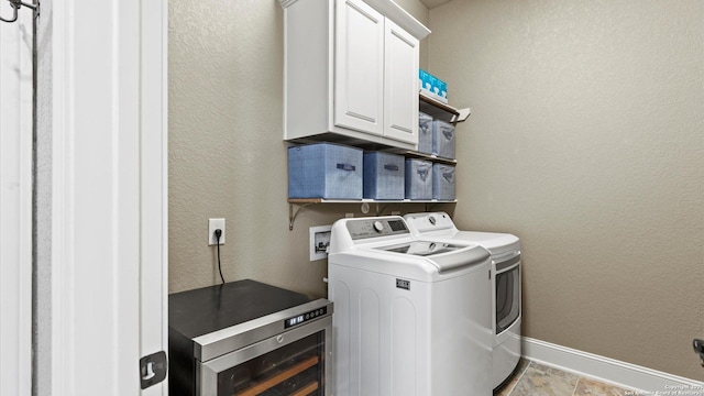 washroom featuring cabinet space, a textured wall, washer and clothes dryer, and baseboards