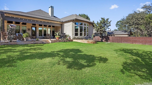 back of house featuring a patio area, a lawn, a chimney, and fence