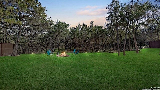 yard at dusk featuring a fire pit and fence