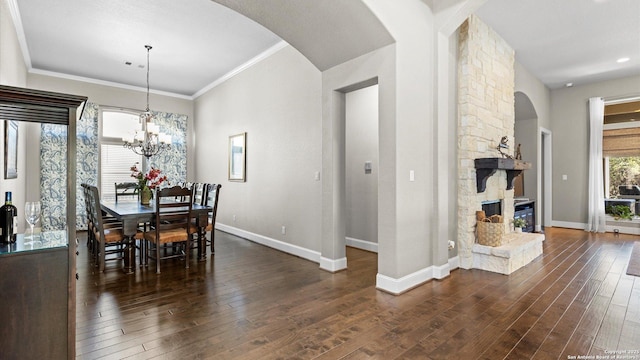 dining area with arched walkways, a fireplace, baseboards, ornamental molding, and dark wood-style floors