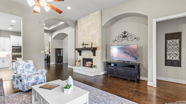 living area featuring a stone fireplace, dark wood-type flooring, and recessed lighting