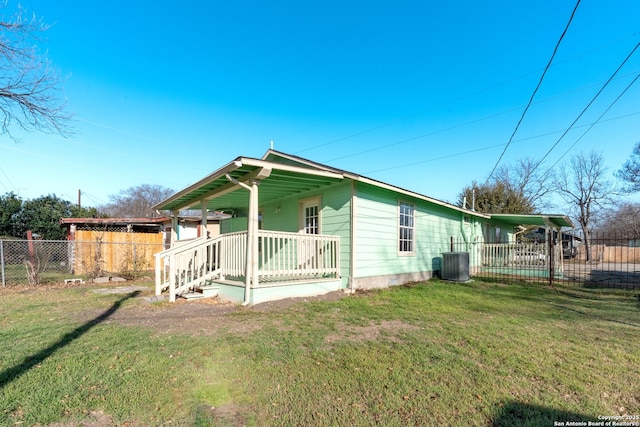 view of side of property with cooling unit, covered porch, a yard, and fence