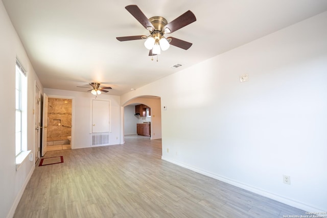 interior space featuring arched walkways, light wood-style flooring, plenty of natural light, and visible vents