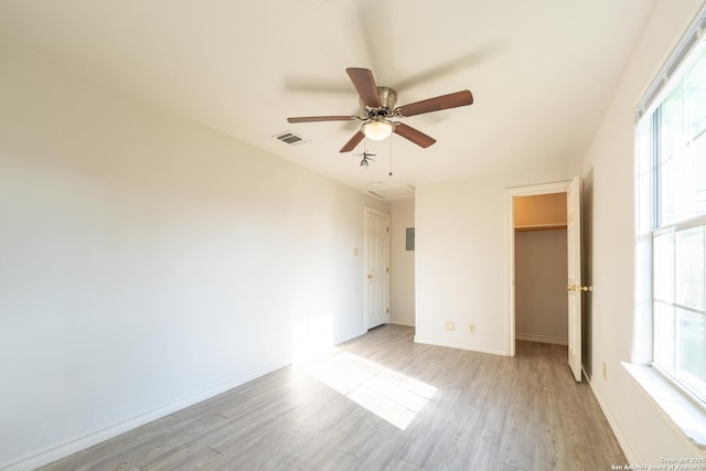 unfurnished bedroom with light wood-style flooring, visible vents, baseboards, a closet, and a walk in closet