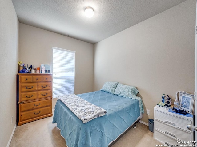 bedroom featuring light colored carpet, a textured ceiling, and baseboards