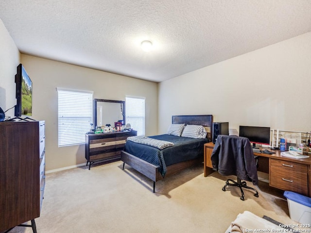 bedroom with light colored carpet, a textured ceiling, and baseboards