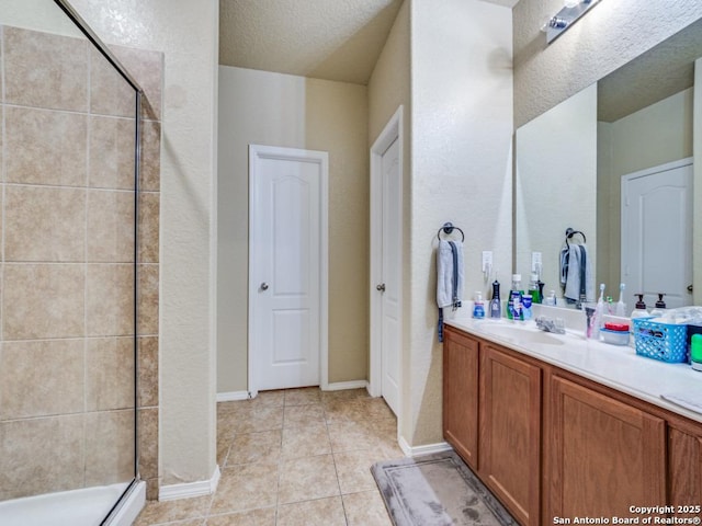 bathroom with tile patterned flooring, a shower stall, vanity, and a textured ceiling