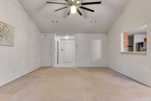 spare room featuring light carpet, vaulted ceiling, visible vents, and ceiling fan